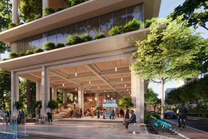 Cafés and shops under a planted colonnade beside a fountain plaza